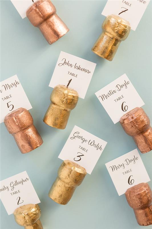 originálna svadobná karta, nápad na recykláciu korkových zátok z farebnej zlatej farby so štítkom s číslom stolu