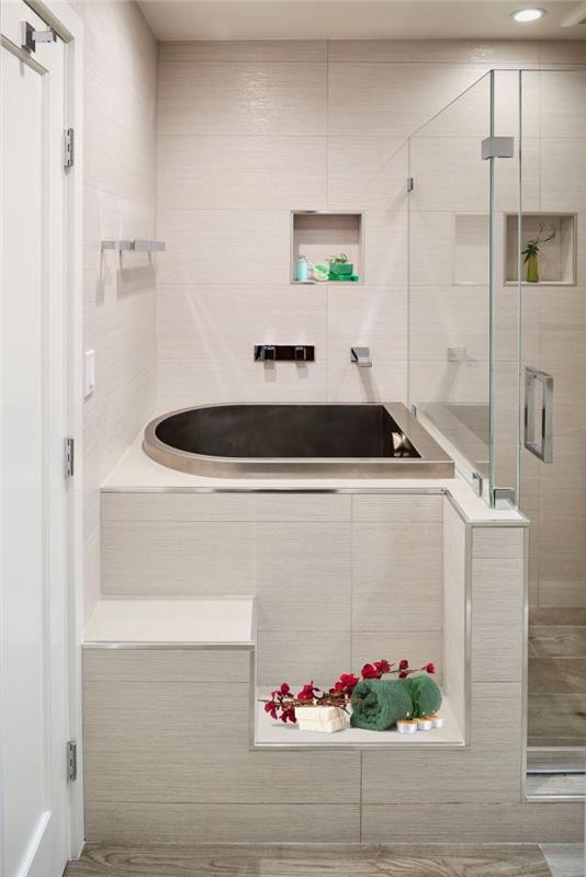 modern badrumsinredning med beige kakel och mini -badkar med metallisk finish, platsbesparande förvaringsidé med väggnischer