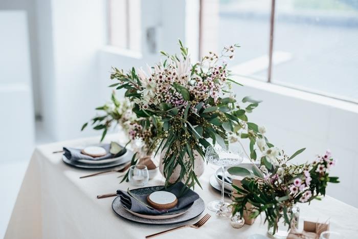 bukett med gröna växter gräs vit rund tallrik svart servett Julbord dekor mässingslock