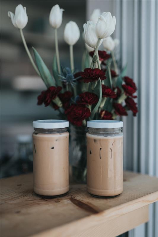 ako si vyrobiť ľahké smoothie, sklenené nádoby naplnené studenou kávou na svetlom drevenom ostrove zdobenom kyticou kvetov