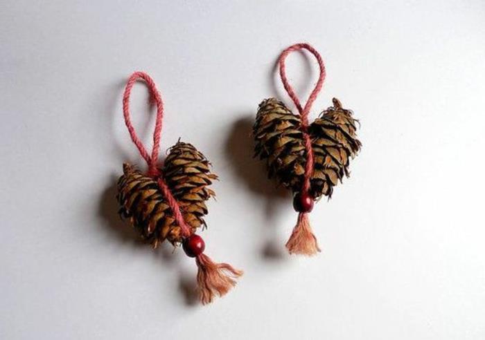 ľahké vianočné remeslá, šišky uviazané v tvare srdca a previazané červenou šnúrkou