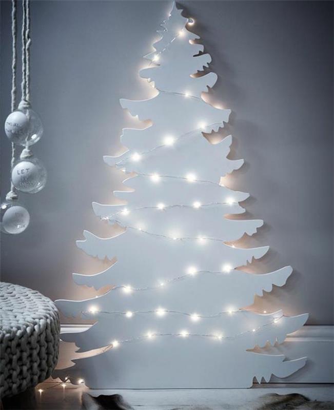 Vianočná dekorácia pre dospelých, biely stromček osvetlený girlandami v bielom svetle, ktorý sa inštaluje k stene
