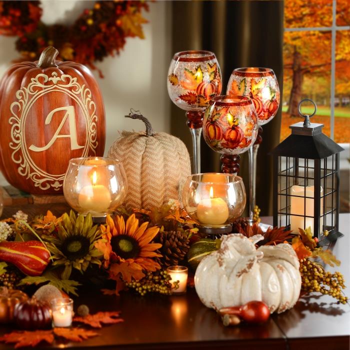 Halloween manuell aktivitet, vita ljus i ovala glasbehållare, apelsin och gröna torkade blad och blommor