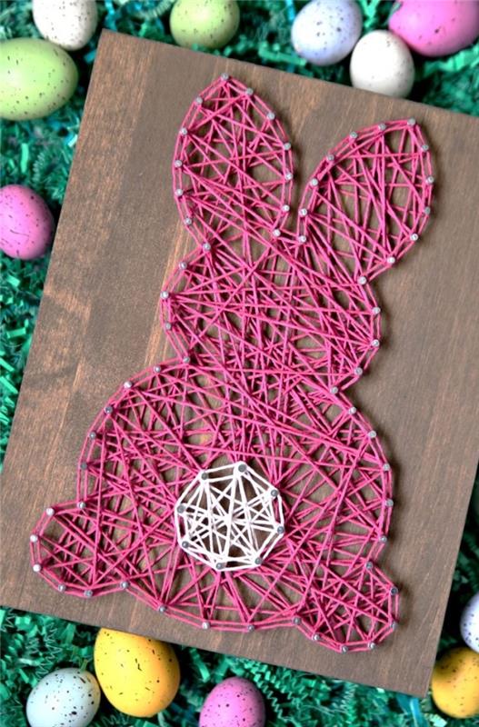 vilken påskdekoration att göra med barnen, modell av ett mörkt träbord dekorerat med rosa och vit tråd i form av en kanin