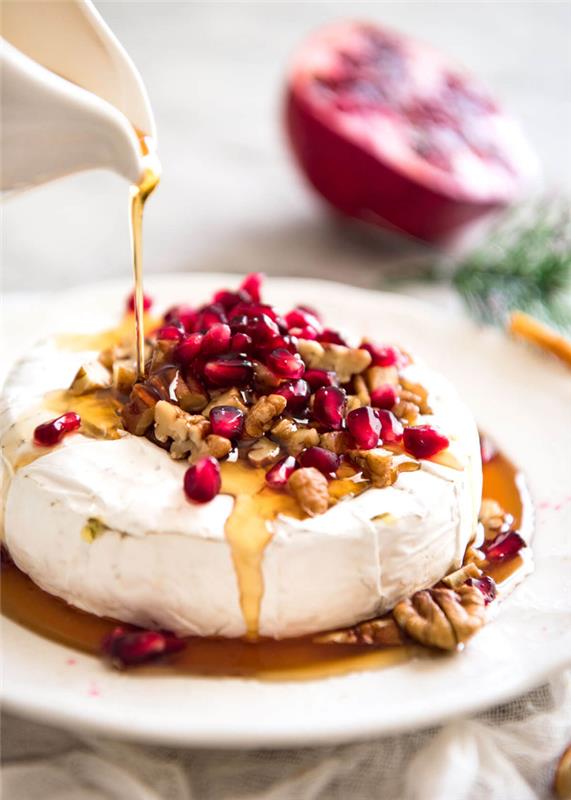 brieost, med honung och granatäpple, hackade nötter, mjölkfria aptitretare, vit tallrik