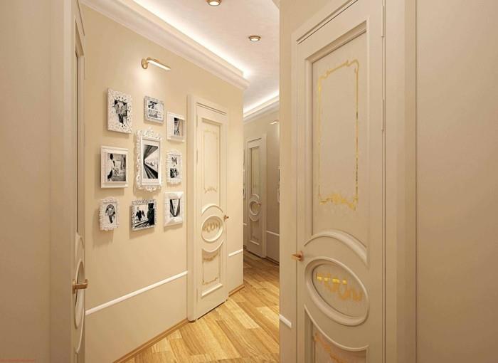 جدران وأبواب قشدية شاحبة ، مع تفاصيل من الجبس ، وزخارف ذهبية ، وديكور المدخل ، وأرضية خشبية فاتحة ، وعدة إطارات بيضاء على الحائط