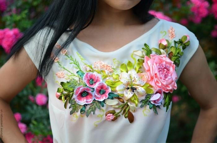 výšivka na oblečení s kvetmi vytvorená zo stužiek dievča v bielom tričku pred ružovým kvetom