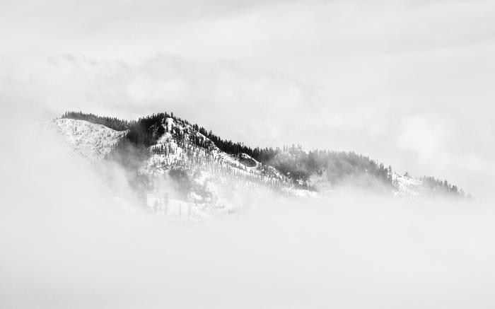 ett vinterlandskap i svartvitt av berg inhöljt i dimma, svartvit landskapsfotografering
