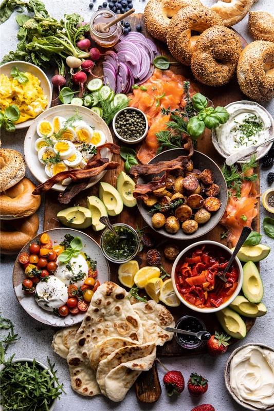 Nedeľný brunch veľa jedla, zeleniny, ovocia, slaniny a rožkov na stole
