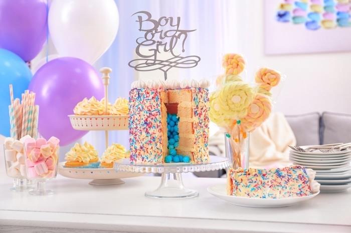 flerskiktad vaniljkaka med blått godis i sitt ihåliga centrum, med färgglada strössel och en baby shower cake topper, söt baby showerbuffé