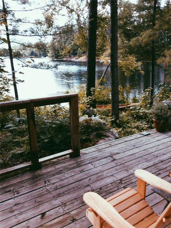 stuga-i-skogen-en-trä-veranda-utsikt-mot-en-sjö
