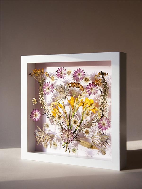 originalidé för en manuell våraktivitet med inramade pressade blommor, vackert bord med torkade blommor med vit ram