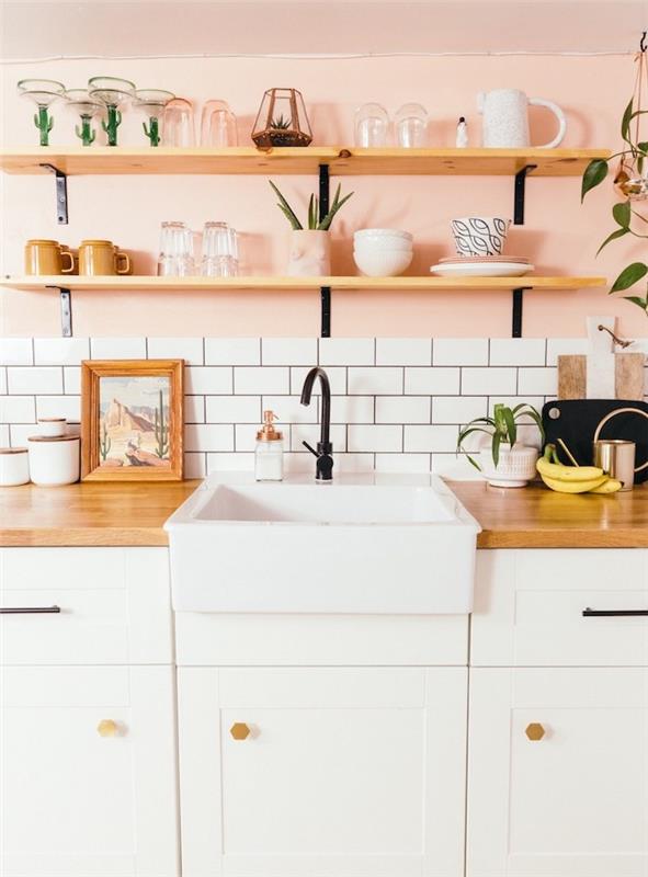 ديكور مطبخ ريفي أنيق مع خزانة بيضاء ، سطح عمل خشبي ، أرفف خشبية ومعدنية على خلفية حائط وردية ، بلاط أبيض