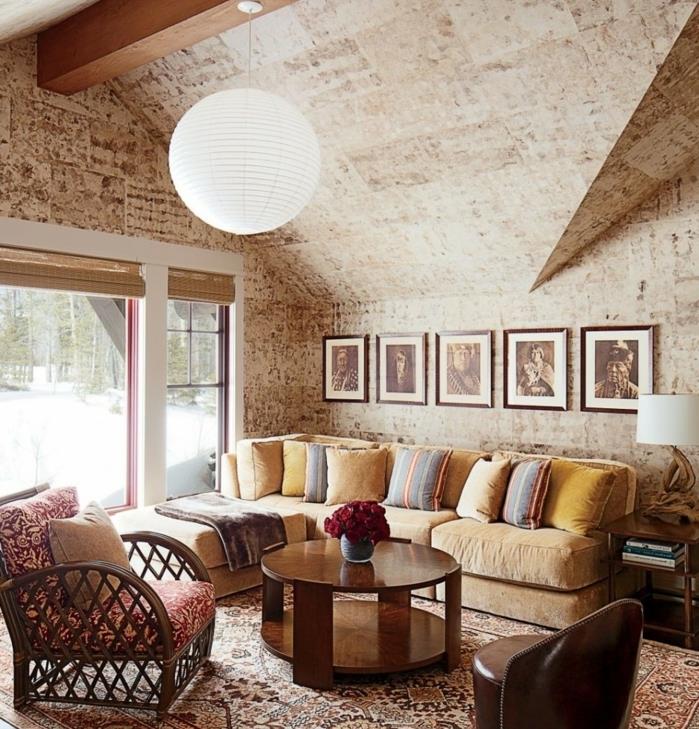 idé hur man ordnar ett rustikt vardagsrum, mångfärgad orientalisk matta, fawn soffa, runt soffbord, sliten lookvägg, inhemska teckningar väggdekoration, design hängande ljus