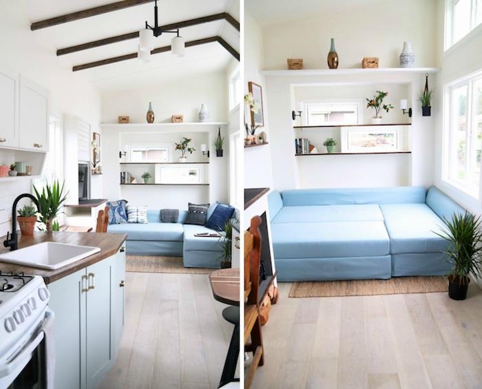 soffa och dubbelsäng i en modulär design i blå färg, vita väggar, små synliga bruna balkar, öppna hyllor, minikök i trä och blått