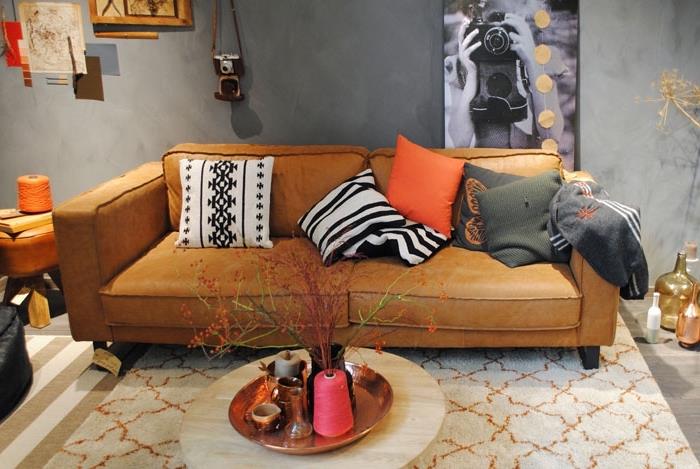 moderný a tradičný interiérový dizajn v obývacej izbe so sivými stenami s pohovkou z ťavej kože a pruhovaným kobercom v bielej a béžovej farbe