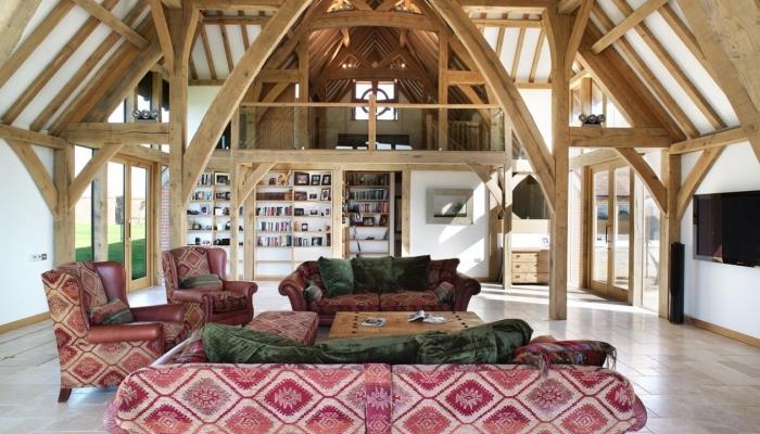 podkrovie v rustikálnom štýle s dreveným stropom a stenami, dekor obývacej izby v bielej a drevenej farbe s červeným a zeleným textilným nábytkom