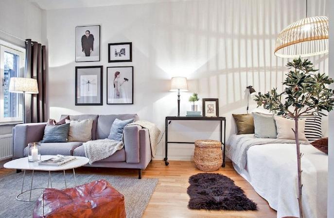 studio layout 30 m2, sovrum med säng bredvid ett litet skandinaviskt nordiskt vardagsrum med soffa, skandinaviskt soffbord, grå matta, vägg av ramar