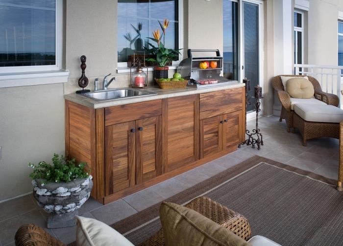 malá kuchyňa vybavená na terase nábytkom z masívneho dreva a ratanu, napríklad kuchynský ostrovček z dreva a nehrdzavejúcej ocele