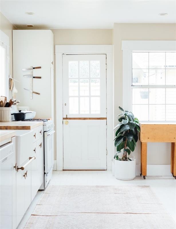 elegantná biela kuchyňa s bielym kuchynským čelom, opotrebovaným orientálnym kobercom, drevenou pracovnou doskou a gumenou nádobou