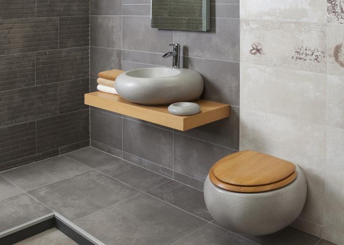 kúpeľňa s obkladmi a sivou podlahou a béžovou stenou s dizajnovým umývadlom a WC