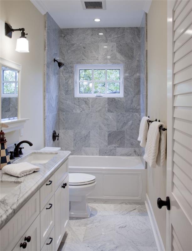 litet badrum med badkar, snygg inredning med marmorplattor och beige väggfärg