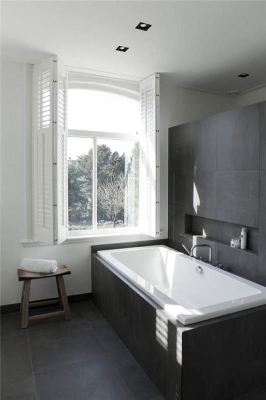 grå-kaklat-badrum-mycket-enkelt-stort-fönster-och-badkar