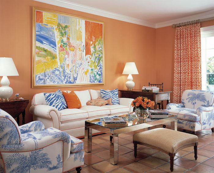 modern inredning, brun läderpall med träben, vit soffa med orange konturer, bukett apelsinrosor, långa gardiner med etniska mönster