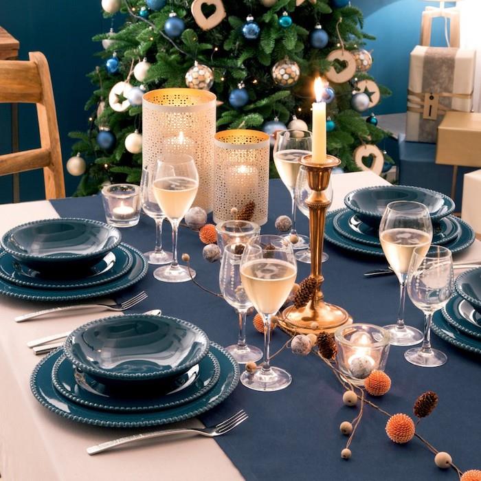 elegant nyårsfestdekoration med blå bordslöpare och blå tallrikar, guldljus, blommig mittpunkt, ursprungliga ljushållare
