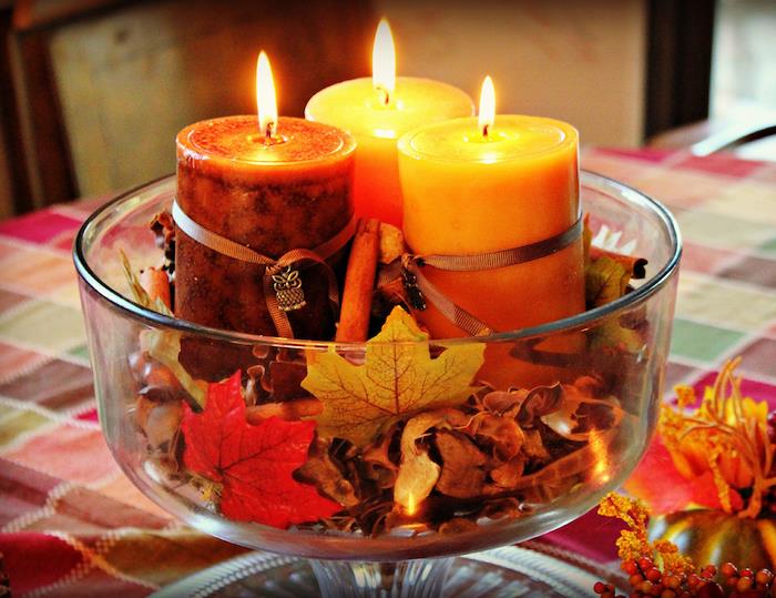 فكرة وعاء زجاجي مليء بأوراق الخريف الميتة وعيدان القرفة والشموع العطرية بالداخل