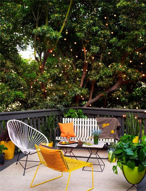 príklad, ako zariadiť záhradu alebo drevenú terasu so železnou lavicou a stoličkami na vajíčka, záhradnou výzdobou s oranžovými vankúšmi a zelenými kvetináčmi
