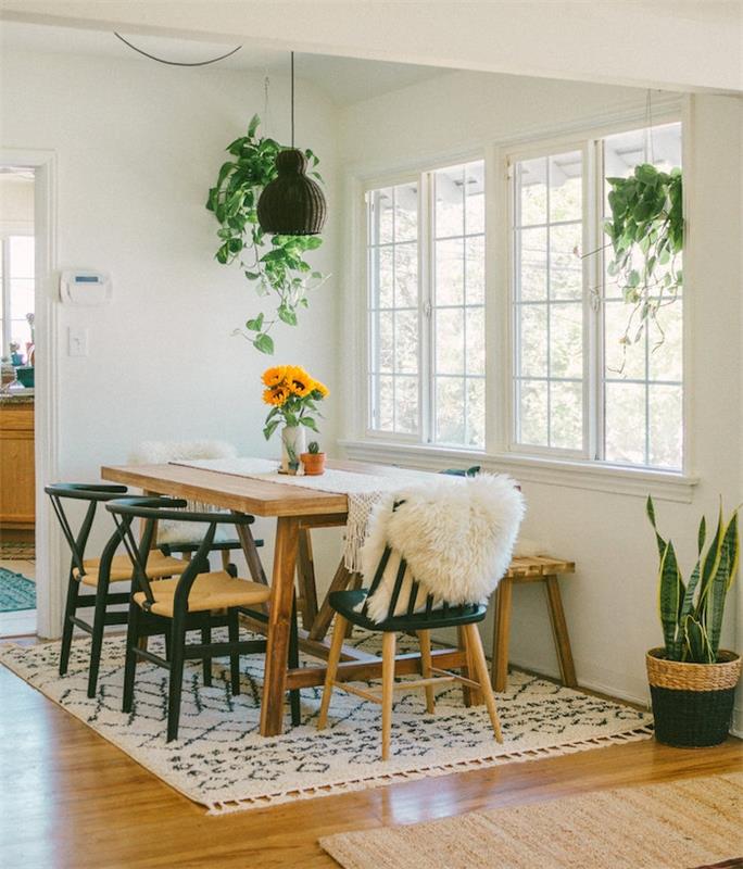 moderná jedáleň so stolom zo surového dreva, drevenými a kovovými stoličkami a čiernobielym kobercom, sansevière v tkanom kvetináči a závesnými kvetináčmi