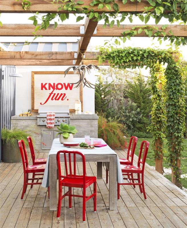 vyvinúť záhradnú kuchyňu s vonkajším nerezovým grilom, záhradným dekorom s červenými stoličkami a tabuľou s dreveným rámom