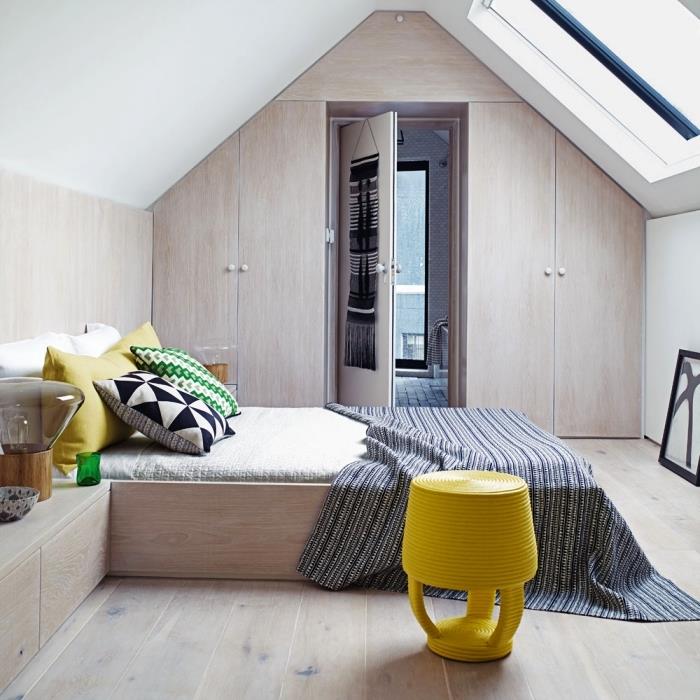 ett sovrum med sluttande tak med en sluttande garderob inbyggd i gavelväggen, vars fasad harmoniserar med resten av möblerna
