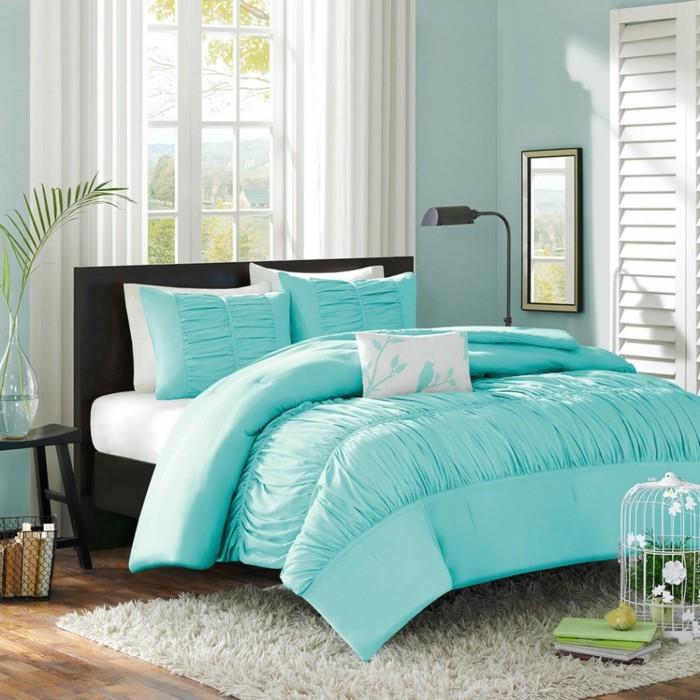 sovrums färgidé, ljusblå väggar, träparkett, turkos sängklädsel