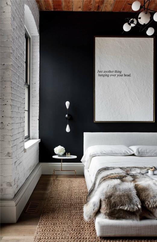 جدار من الطوب المطلي باللون الأبيض في غرفة النوم ، لوحة مع نص مثير ، غطاء سرير من الفرو ، سجادة ريفية ، فكرة لطلاء غرفة النوم