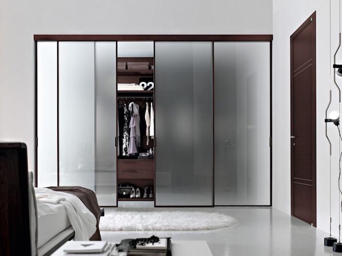 minimalistisk vit sovrumsinredning och mörkbruna möbler