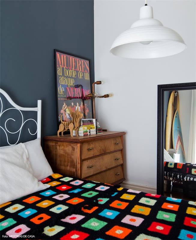 sivobiely model spálne, sivá akcentovaná stena, vintage drevená komoda, obdĺžnikové zrkadlo, kovová biela posteľ s čiernym poťahom s farebnými geometrickými vzormi
