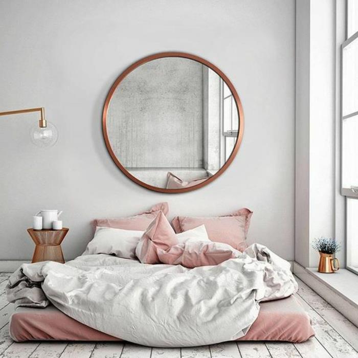 غرفة نوم باللون الرمادي والوردي ، أرضية خشبية رثية ، مرآة مستديرة ، طاولة سرير نحاسية ، مرآة مستديرة نحاسية