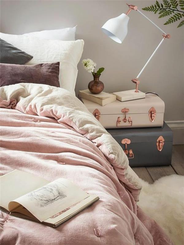 غرفة نوم باللونين الرمادي والوردي ، وحقائب عتيقة ، ومصباح أبيض ، وحقائب عتيقة بجانب السرير