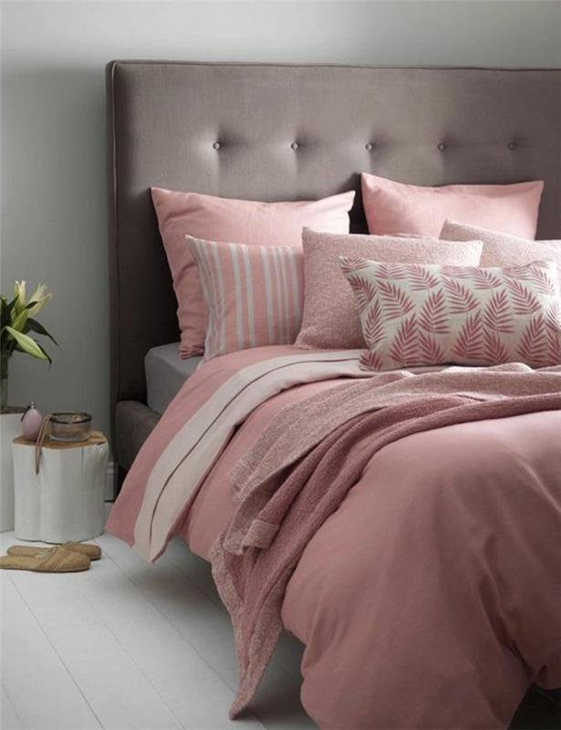 غرفة نوم باللون الرمادي والوردي ، وسائد باللونين الوردي والأبيض ، ولوح رأسي مبطن باللون الرمادي ، وجانب السرير الخلفي