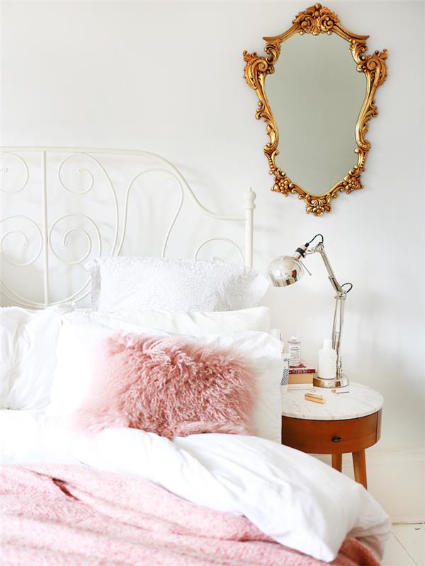 dekoration av ett flickrum i vit sänglampa av metallisk effekt, pastellrosa filt i pälspäls och kudde
