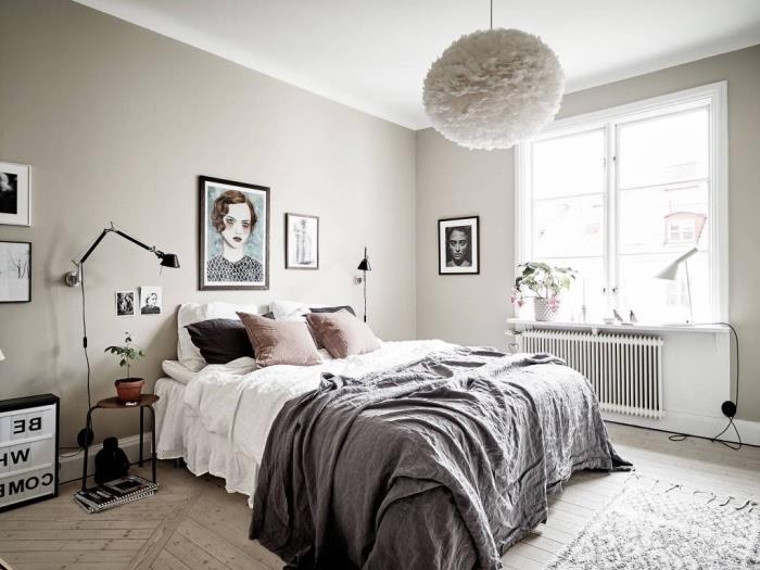 Škandinávsky nápad na výzdobu v spálni, sivá a biela posteľná bielizeň s ružovými vankúšmi, svetlé parkety, koberec a sivá stena, portrétna žena