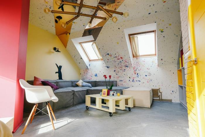 moderné a umelecké usporiadanie spálne v podkroví s jasnými farebnými akcentmi na stenách a nábytkom v škandinávskom štýle s paletovým konferenčným stolíkom