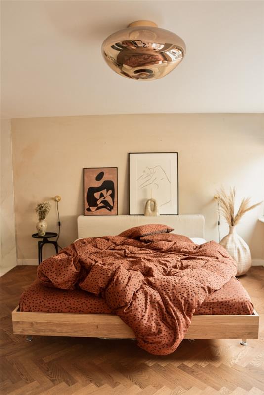 terakotová spálňa posteľná bielizeň dekorácia kokonová posteľ dizajn interiéru minimalistický štýl biela váza origami okrúhly matný čierny nočný stolík