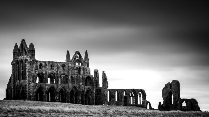 nostalgiskt svartvitt landskap med utsikt över ruinerna av klostret whitby i england mot grå himmel bakgrund