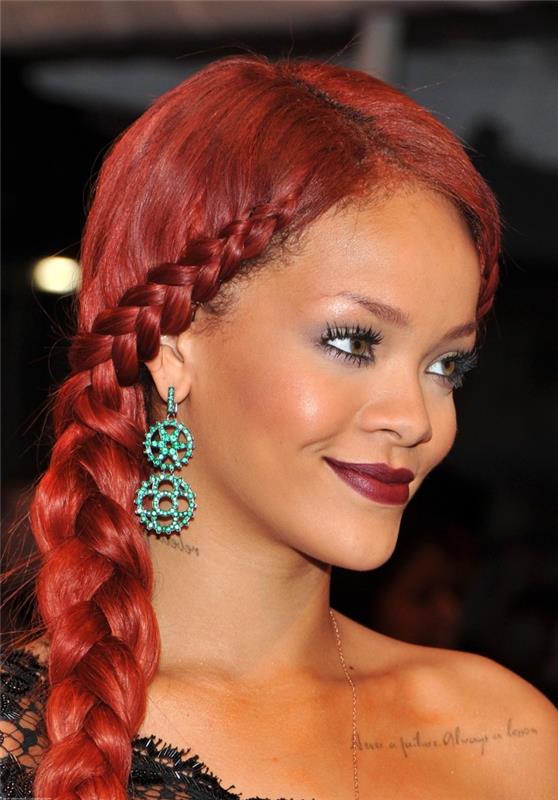 Účes Rihanna s dlhými červenými vlasmi uviazanými na boku, príklad účesu s africkým vrkočom na boku