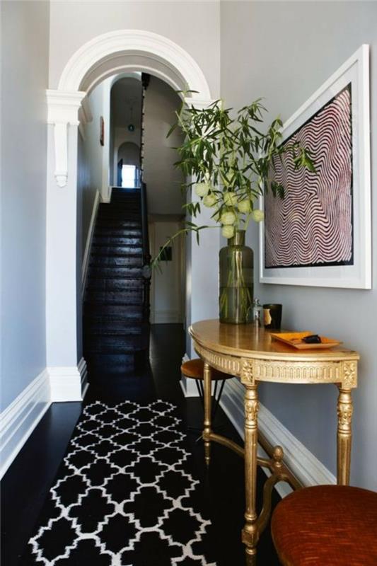 Svart golv och grå väggar, smalt hallskåp, enkel och effektiv dekoration, vas med blommor på ett halvrunt bord