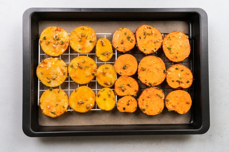 Patate sottili al forno, teglia con fette di patate dolci, teglia con rete e carta da forno