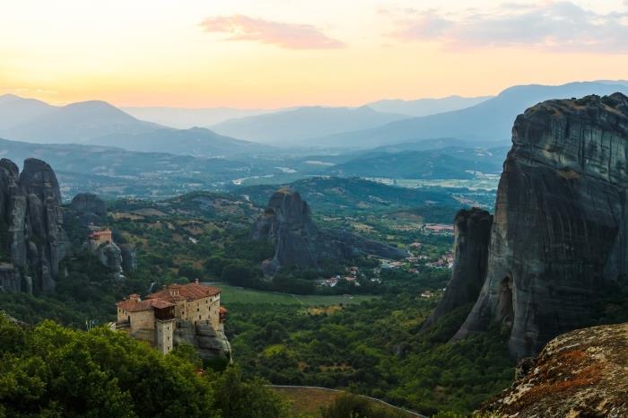 fotografia turistickej lokality Meteora v Grécku, pohľad zhora na vzdialené hory a dedinu pri východe slnka